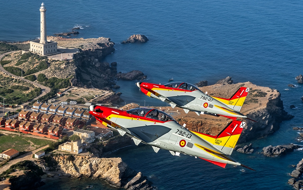 Two Pilatus training aircraft flying over the coast.